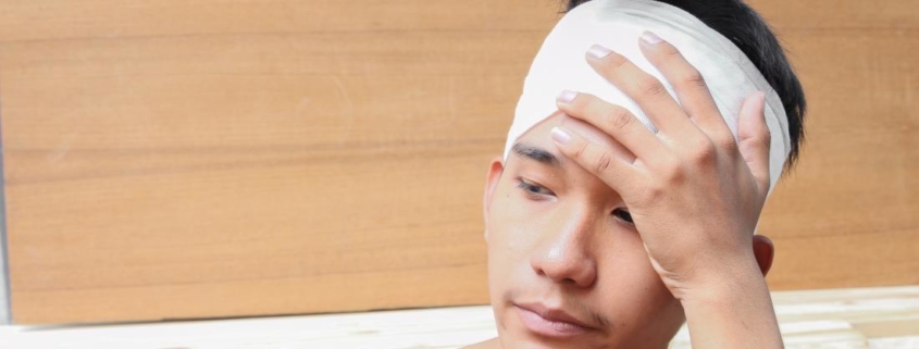 man with head injury from cat accident holding bandage on head