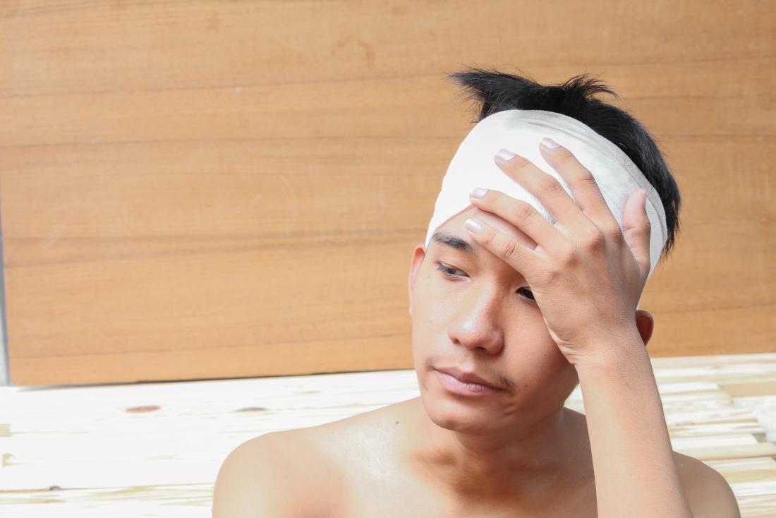 man-with-head-injury man with head injury from cat accident holding bandage on head